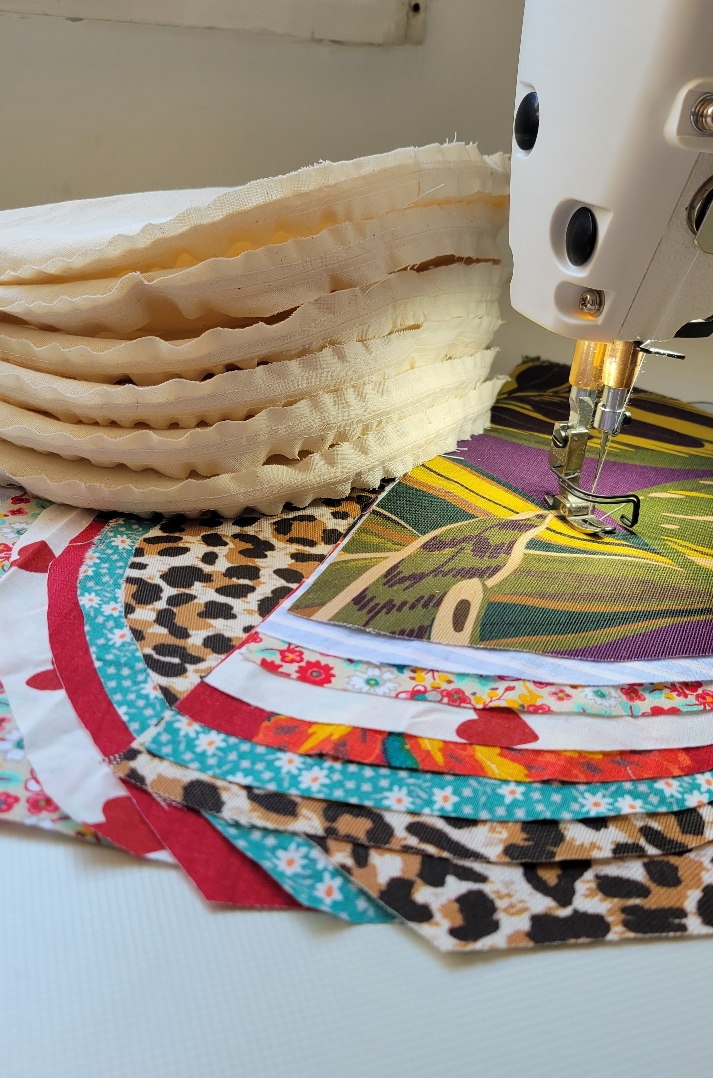 Piles de tissus chinés posées sous la machine à coudre